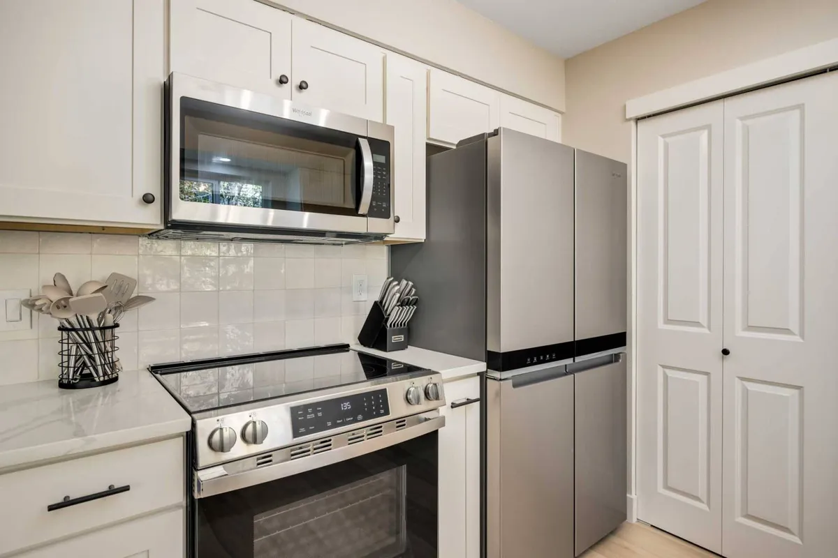 The image focuses on a sleek kitchen featuring stainless steel appliances, white cabinetry, and elegant quartz countertops. The layout is functional yet stylish, providing an ideal setting for culinary experiments and family meal preparation.