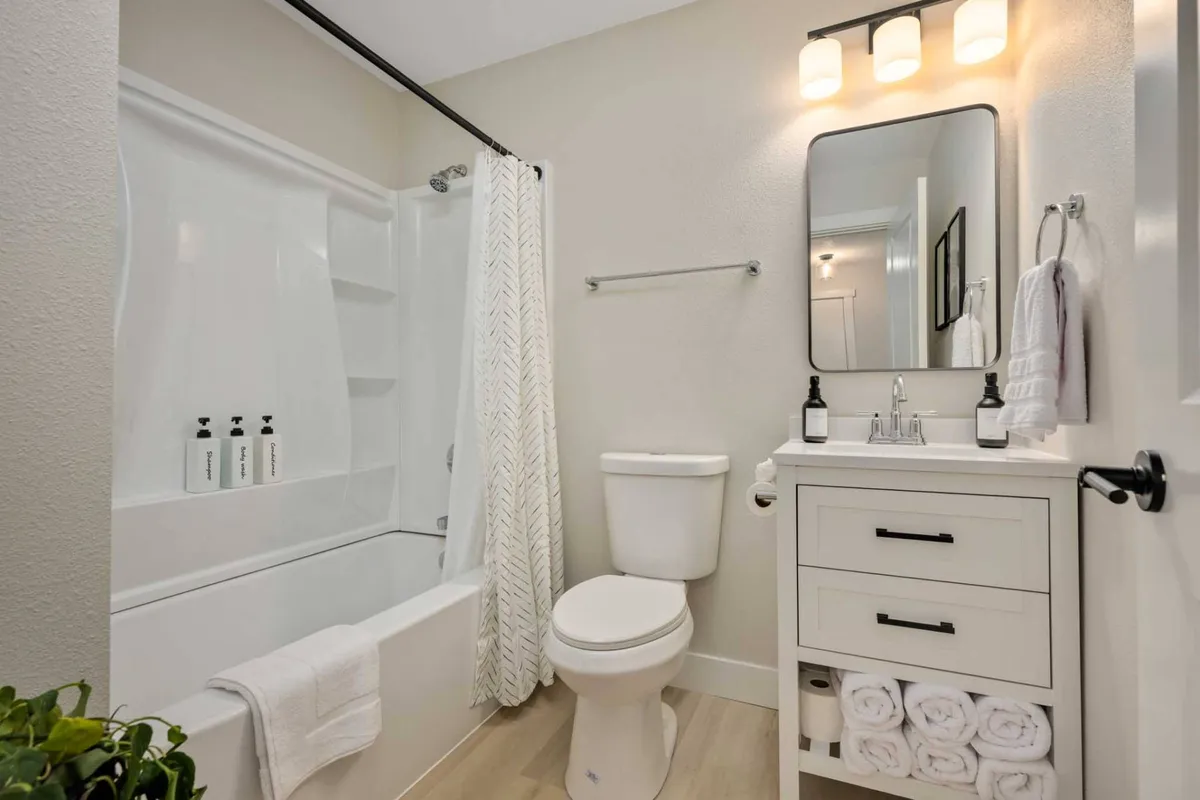 A beautifully tiled bathroom with a modern bathtub, a well-lit vanity and mirror, fresh towels, and potted plants. The scene evokes relaxation and self-care, with a subtle spa-like feel and soothing colors.